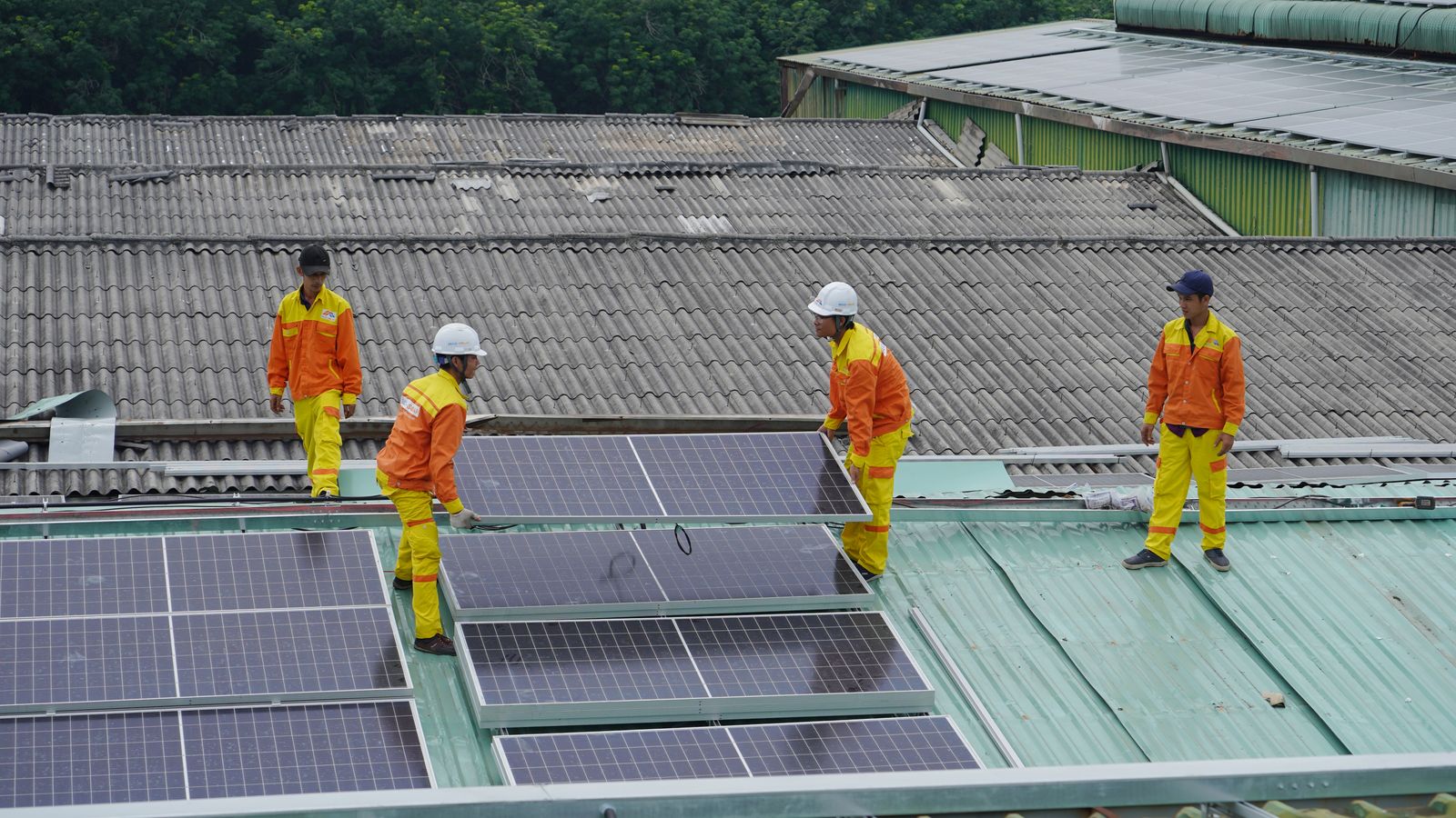 Monteure verlegen Solarmodule auf einem Hallendach